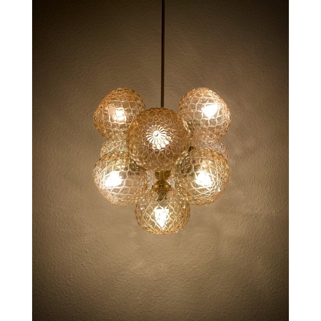 A classic mid-century design, this Sputnik-style chandelier features hand-blown bubble glass in a warm amber tone,...