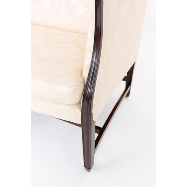An elegant Georgian mahogany settee of fine quality, raised on eight tapered, fluted legs united by an H-frame stretcher...