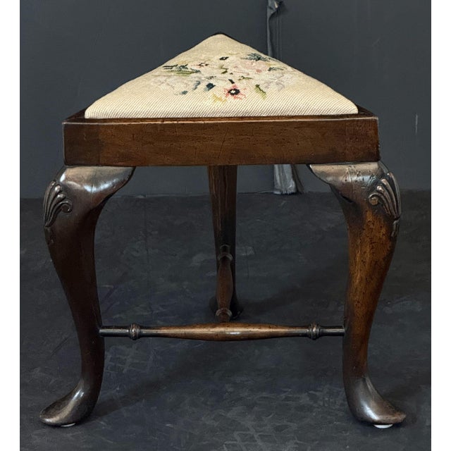 A fine English three-sided stool of patinated walnut from the Edwardian era, featuring a triangular inset upholstered...