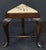 A fine English three-sided stool of patinated walnut from the Edwardian era, featuring a triangular inset upholstered...