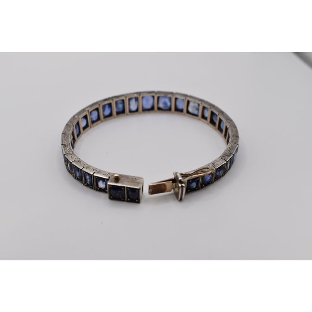 A sapphire bracelet from the early 20th century comprising a single row of 32 graduated cushion cut blue sapphires. They...