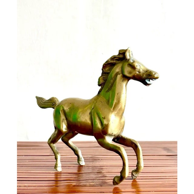 This brass horse sculpture captures a moment of dynamic motion, its legs mid-gallop and mane swept back as if caught in...