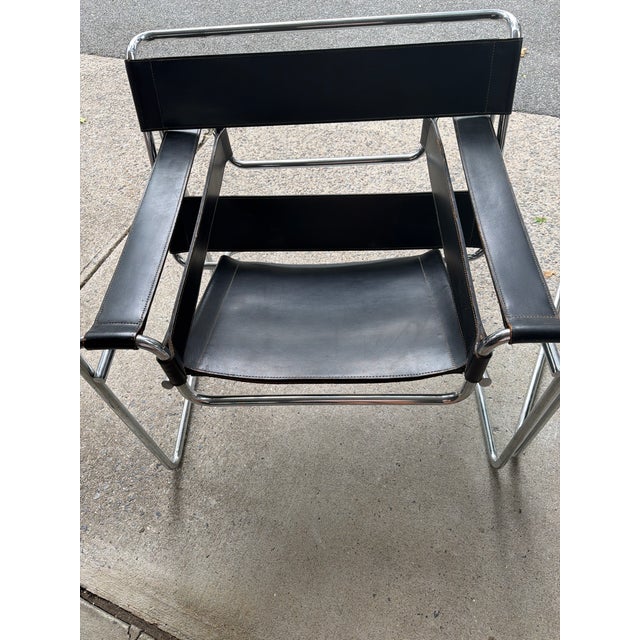 Matching pair of vintage Italian black leather and tubular chrome lounge chairs, dating to approximately the 1980s. The...