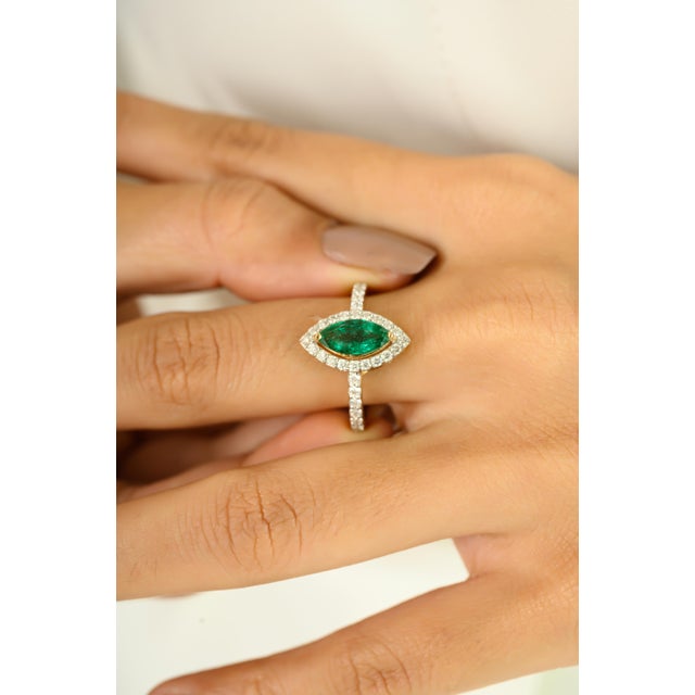 Radiating timeless elegance, this exquisite ring features a vivid 1.05 carat marquise-cut emerald, framed by a halo of...