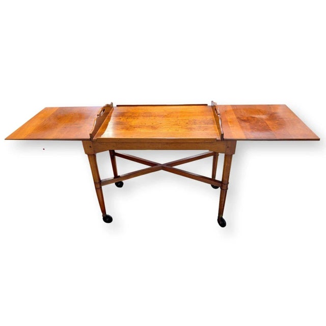 This solid cherry server features a colonial-inspired frame with turned legs, cross-bracing, and smooth caster wheels for...