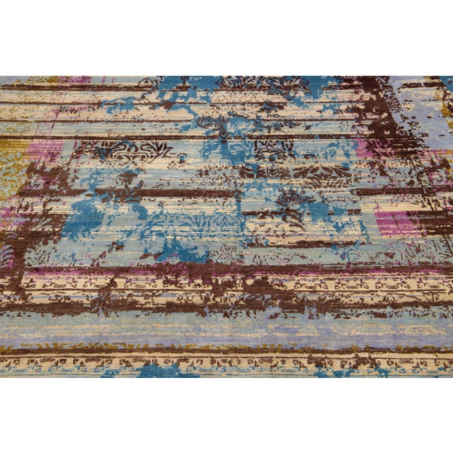 This Tibeto-Indian wool and silk blend rug features a light gray and beige field with an abstract pattern detailing blue,...