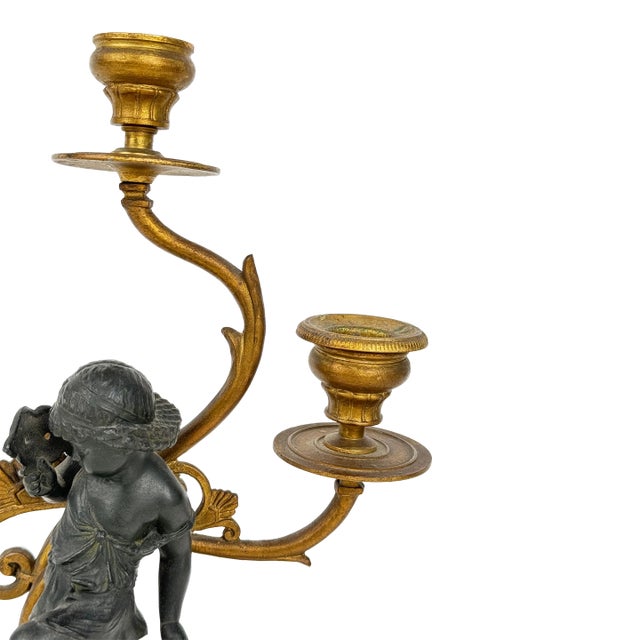 A pair of French gilt bronze and patinated bronze candelabra, 19th Century. The candelabra have two types of bronze...