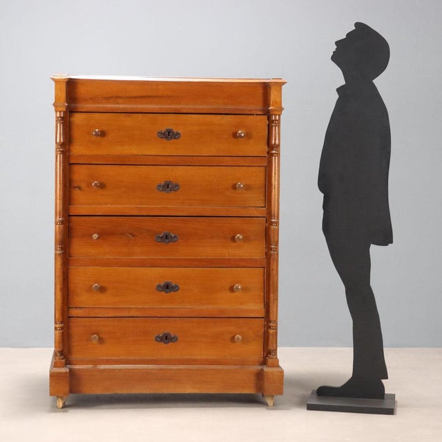 Umbertino walnut chest of drawers. Front with five stacked drawers, flanked by turned uprights, wooden knobs, and worked...