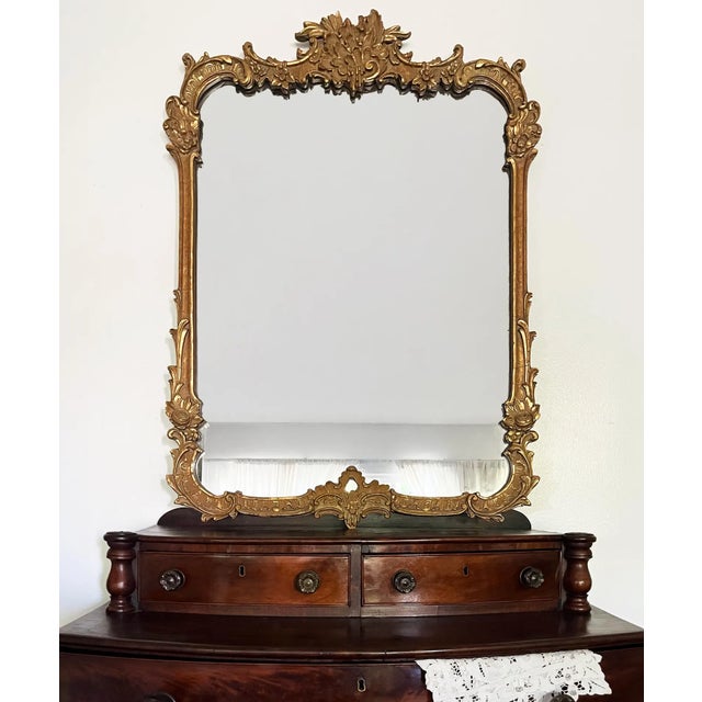 A beautifully crafted antique French Rococo Revival mirror featuring richly detailed gesso ornament and an elegant...