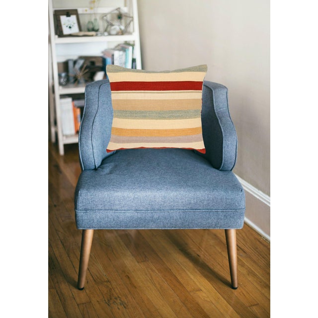 A one-of-a-kind handwoven wool kilim floor pillow featuring a vivid multi-stripe of red, teal, gold, and lilac. Fully...