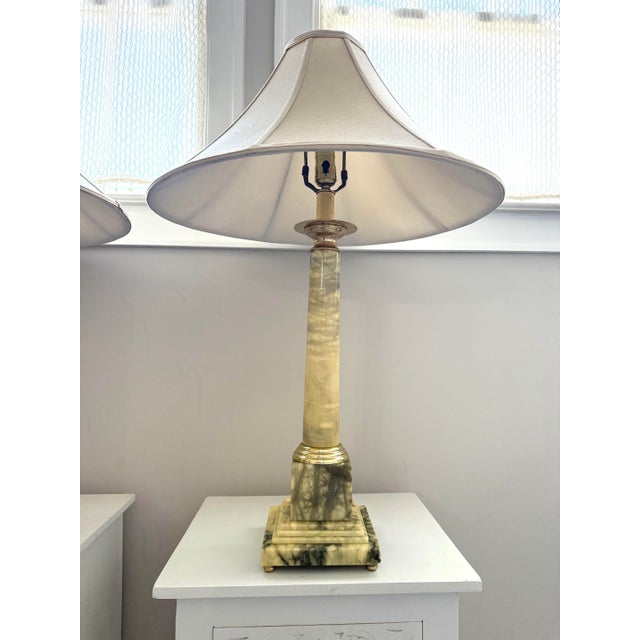 An incredibly elegant matched pair of mid-century table lamps carved from solid onyx marble, each featuring a stepped...