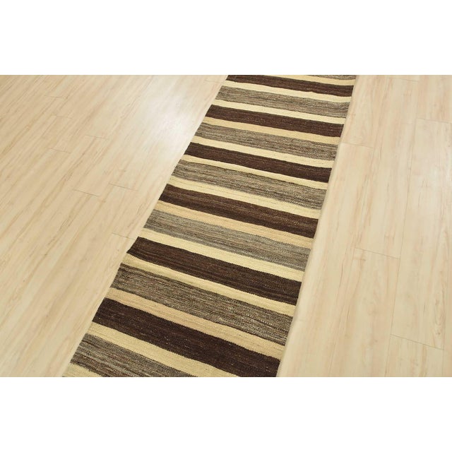 A contemporary Kilim runner handwoven with wool on a cotton foundation. This rug features horizontal stripes. It is new...