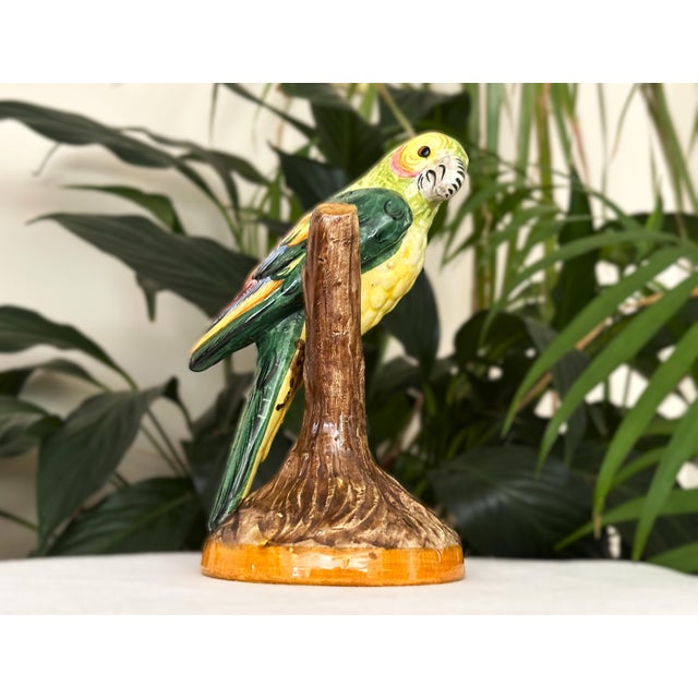 A vibrant, vintage Italian ceramic parrot figurine, beautifully hand-painted with bright mid-century tropical flair. The...
