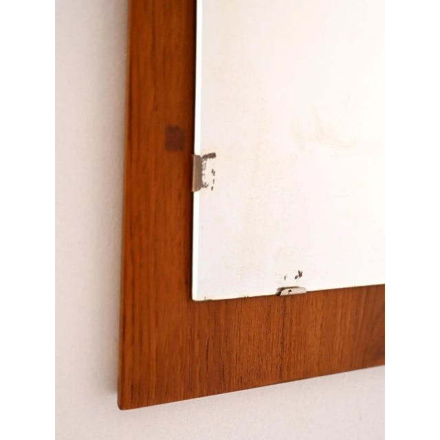 Wall mirror with teak frame and glass secured with metal clips, Scandinavian production from the 1960s. Wall mirror made...