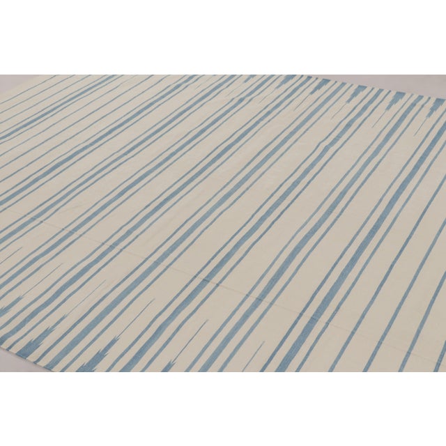 This 8x10 Dhurrie rug features horizontal stripes in ivory and blue, representing an exciting contemporary flatweave...