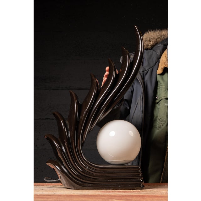 c. 1980s Sculptural ceramic table lamp formed as a dramatic, upward-sweeping wing or flame motif, cradling a spherical...