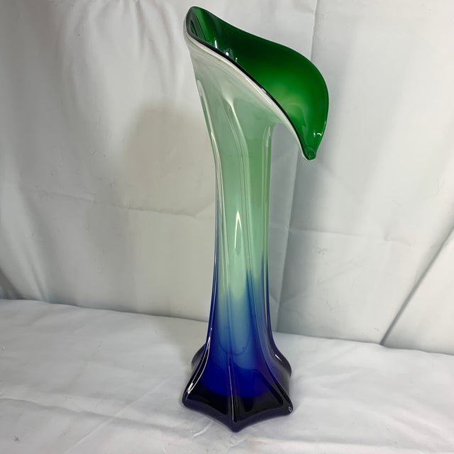 This is a hand-blown art glass vase featuring a flared, calla-lily or Jack-in-the-pulpit style rim with a gradient blue,...