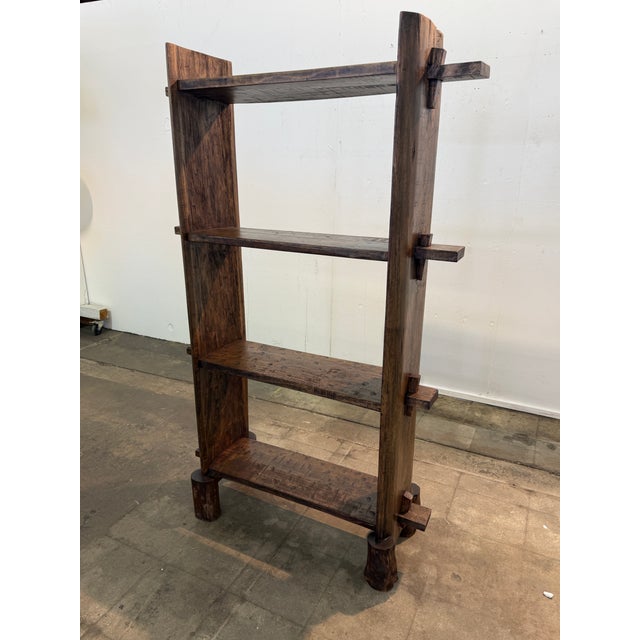 Striking Brutalist-style open shelving unit crafted from solid wood, featuring a bold, architectural silhouette and...