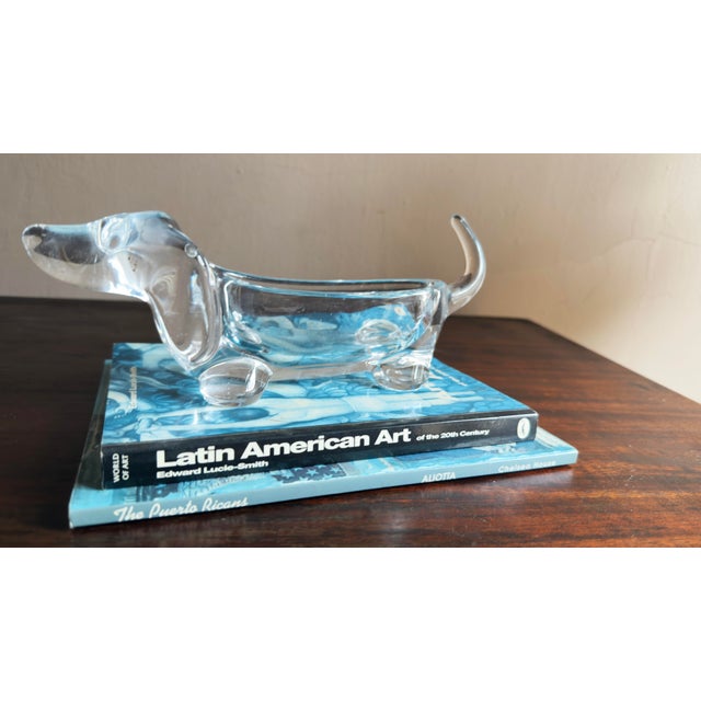 This vintage Mid-Century Modern piece is a clear glass dachshund-shaped dish, likely made from pressed glass or heavy lead...