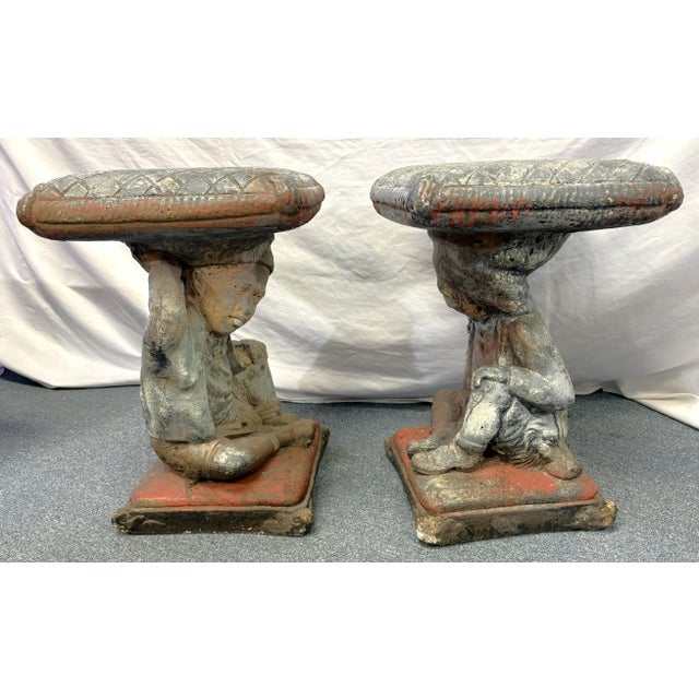 Spectacular pair of figural putti garden stools from the mid 20th century. The playful putti are positioned with one bent...