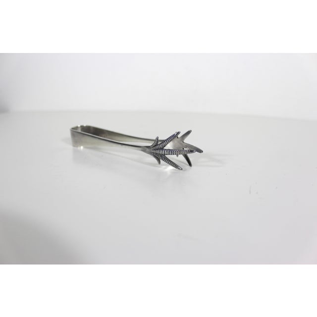 Small vintage silver plated sugar tongs with bird claw tips. They have tarnish, scratches and patina from age and use....