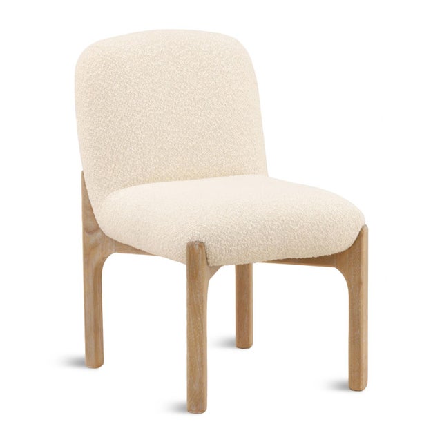 Upholstered in a soft ivory boucle fabric, this dining chair has a gently curved backrest and generously cushioned seat...