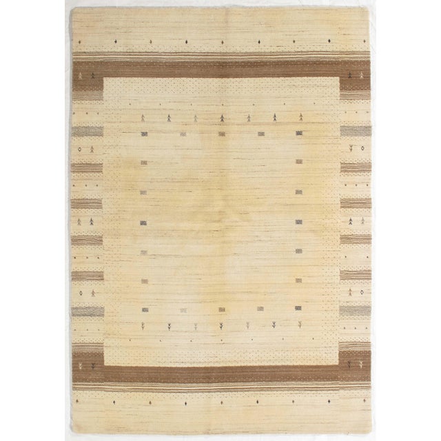 Vintage Hand-knotted Gabbeh rug featuring a soft, neutral field framed by subtle geometric borders in warm brown tones....