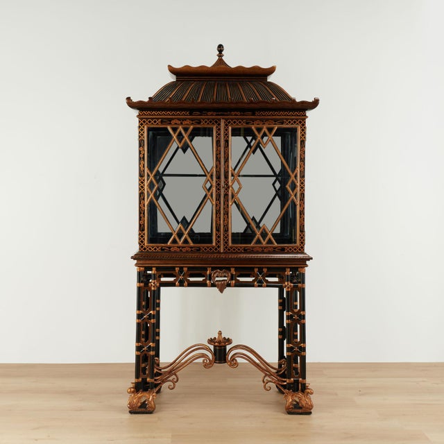 Standout vintage black and gold Chinese Chippendale style cabinet, handcrafted in hardwood with a dramatic pagoda top. The...