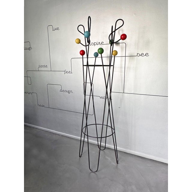 An iconic example of French Mid-Century design, featuring a black lacquered steel wire structure adorned with brightly...