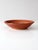 This vintage studio pottery bowl features a warm terra-cotta orange glaze with subtle black etched stripe accents along...