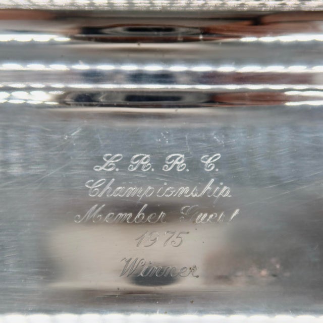 A 1975 club trophy in the form of a long, two-handled silverplate bread tray by Poole Silver Co. The center is engraved in...