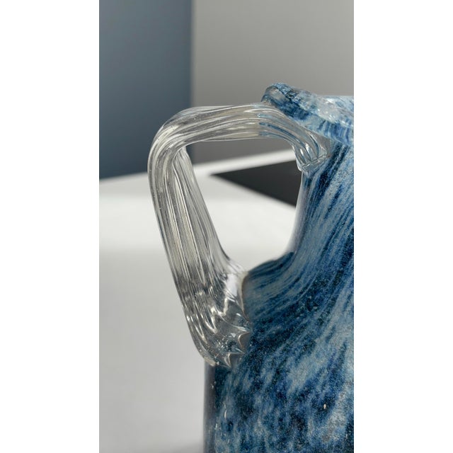 A beautiful decorative carafe in blown glass, its deep blue body streaked with white veins and clouds that create a...
