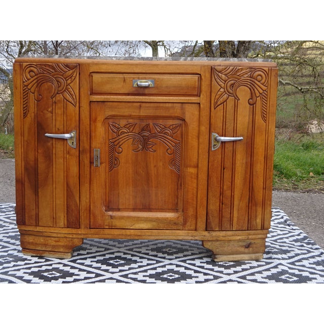 Art Deco style sideboard in solid walnut. Slightly curved front; 3 doors and 1 drawer. Carved floral motifs, decorative...