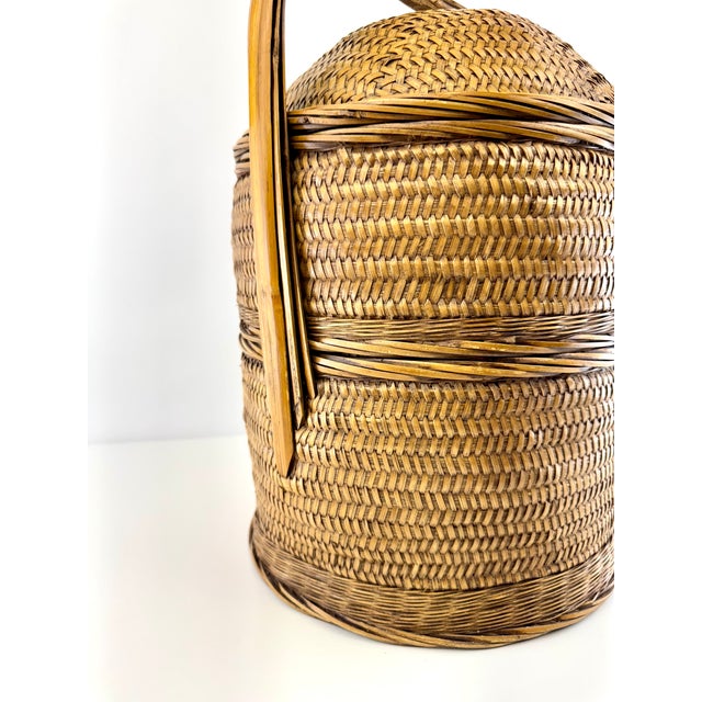 Mid-century table lamp crafted from tightly woven rattan with sculptural bamboo-form framing and warm brass hardware. The...