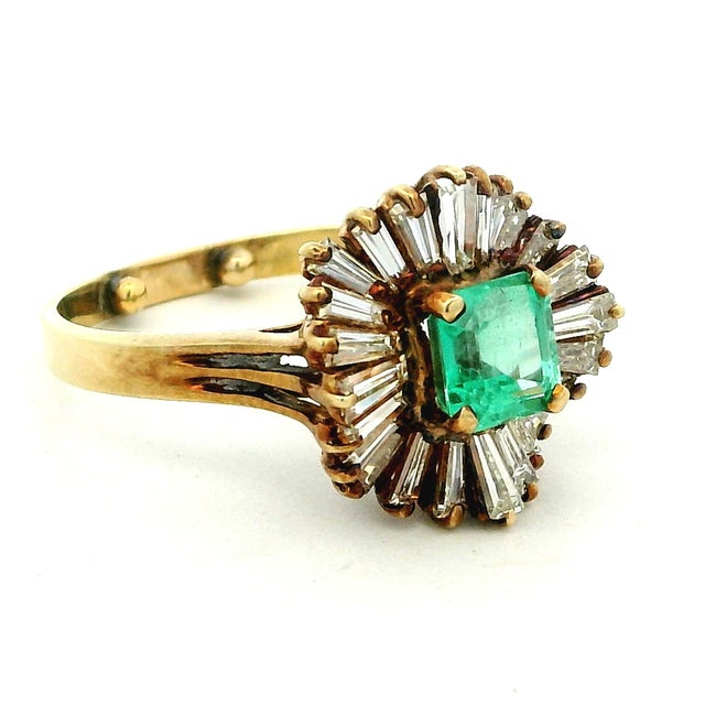 An elegant circa 1980 ballerina ring crafted in 14K yellow gold, centered by a 0.88 carat rectangular step-cut emerald....
