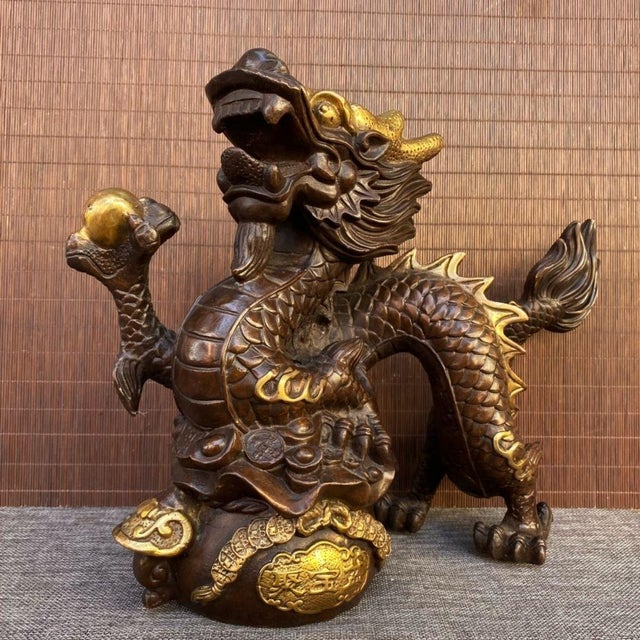A striking Chinese bronze sculpture featuring a dynamic dragon perched atop a treasure basin. The dragon is intricately...