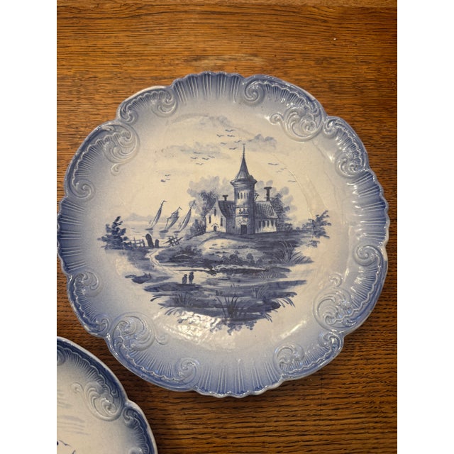 Listing is for a pair of blue and white plates with hand painted scenes that depict vessels on a waterfront and the other...