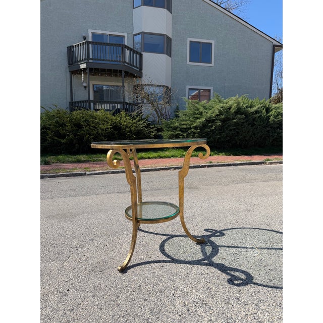 Hollywood regency style gilt iron two tiered side table. The table is in the style of Maison Ramsey. Dimensions: H: 29.25”...