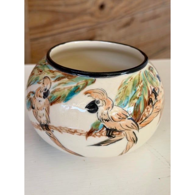 A charming vintage hand-painted ceramic bowl or cachepot featuring playful cockatoos perched among tropical foliage. The...