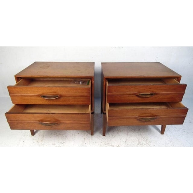 Mid-Century Modern walnut nightstands with sculpted wood handles. Two drawers with brass trim handles.