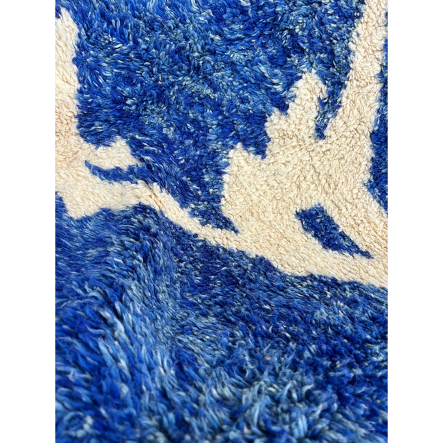 A striking handcrafted M’rirt rug featuring an expressive abstract design in deep cobalt blue and natural ivory. Its bold...