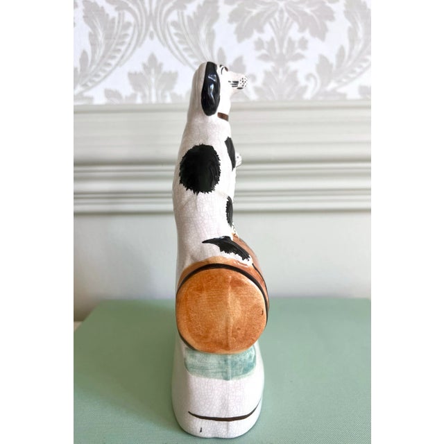 A charming pair of black-and-white Staffordshire-style spaniels sharing a single base — a classic symbol of loyalty and...