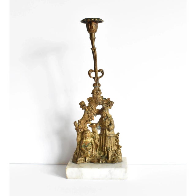 An antique Victorian bronze ormolu candlestick holder on a white marble base. The bas relief bronze pastoral scene is of...