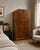 An Art Deco wardrobe in beautifully figured walnut with dramatic bookmatched grain, stepped cornice and original sculpted...