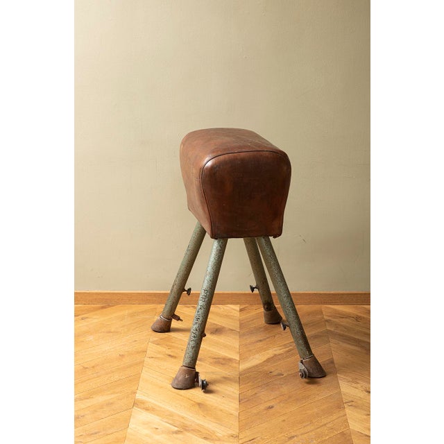 Gym vaulting horse used in gymnasiums. Seat made of brown leather. Structure based on four metal legs with metal feet....