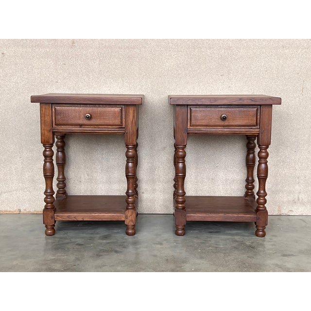 20th century Pair of solid carved Spanish nightstands with turned columns and low shelve. It has one carved drawer with...