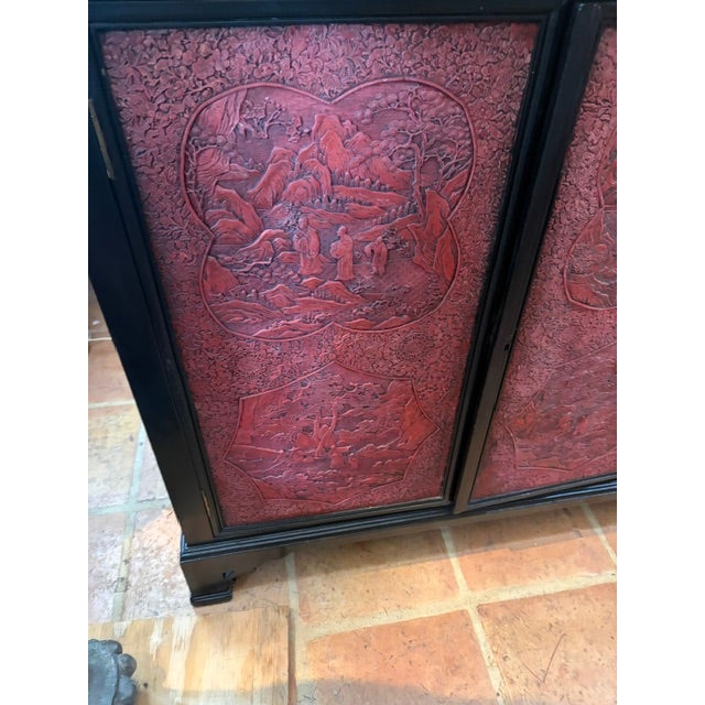 The product is a rare large Asian black lacquer and cinnabar four door server, measuring 70 inches long. This vintage...