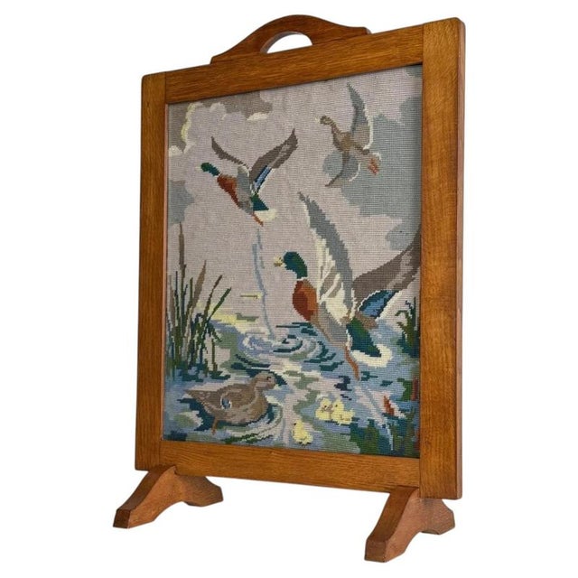 A charming early 20th-century English fire screen, finely crafted from oak and centred with a decorative tapestry panel...