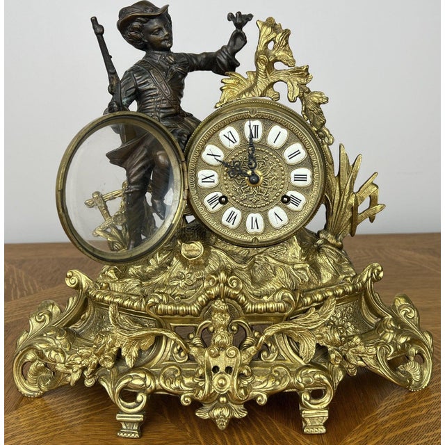 A highly decorative Vintage brass clock featuring an ornate figurative design with an elegant seated figure beside the...