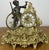 A highly decorative Vintage brass clock featuring an ornate figurative design with an elegant seated figure beside the...
